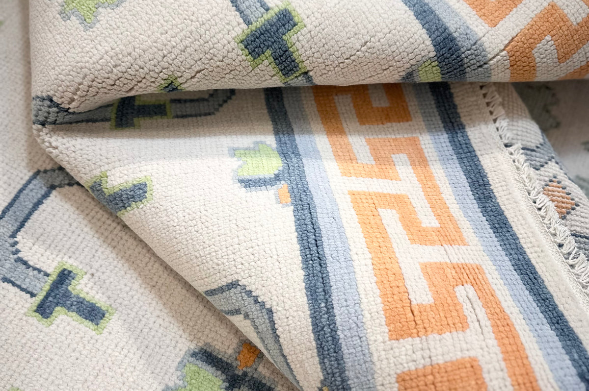 Close-up of oushak wool rug with Greek key design in orange and blue
