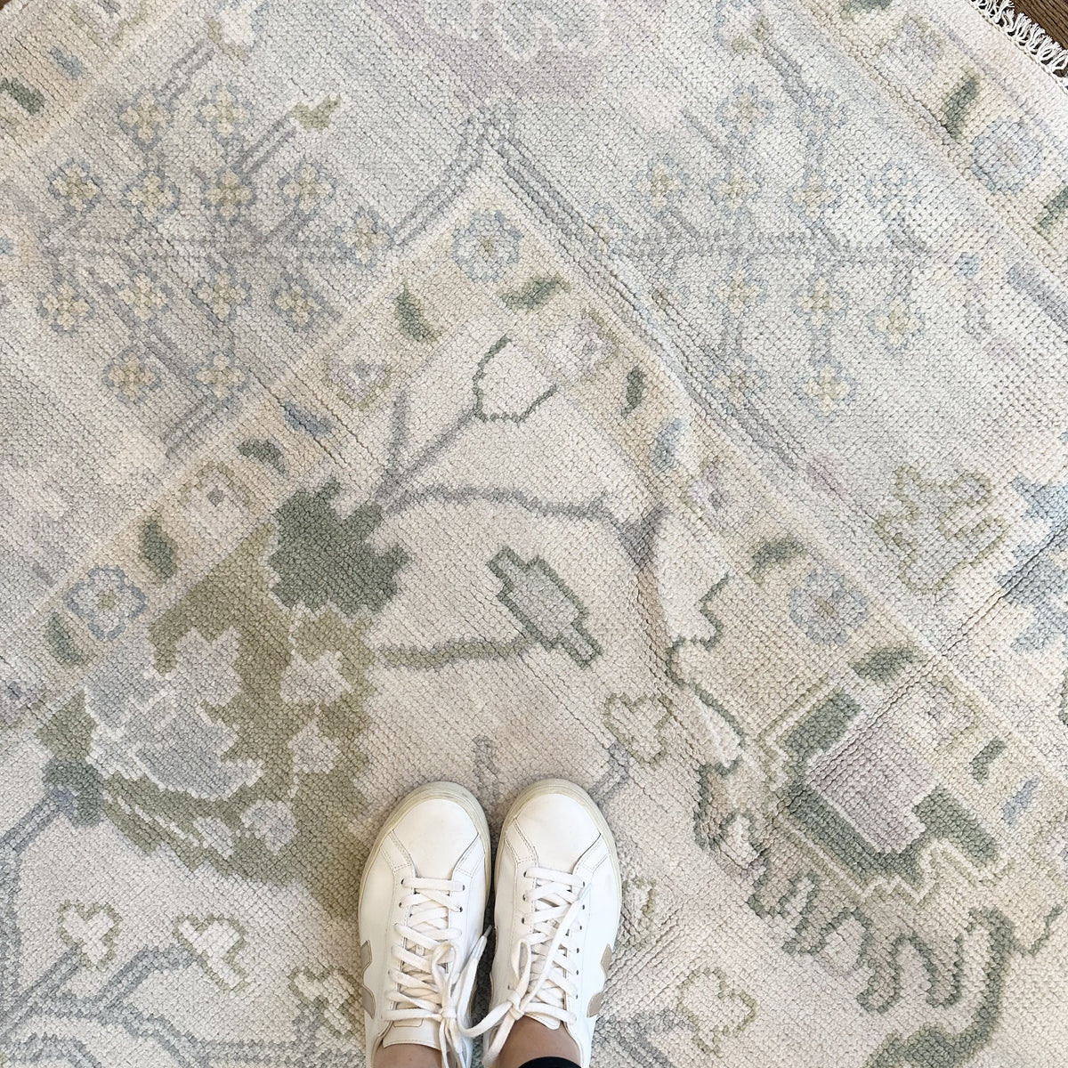 A close-up view of a Modern Oushak rug featuring a geometric pattern in green, blue, and beige tones.
