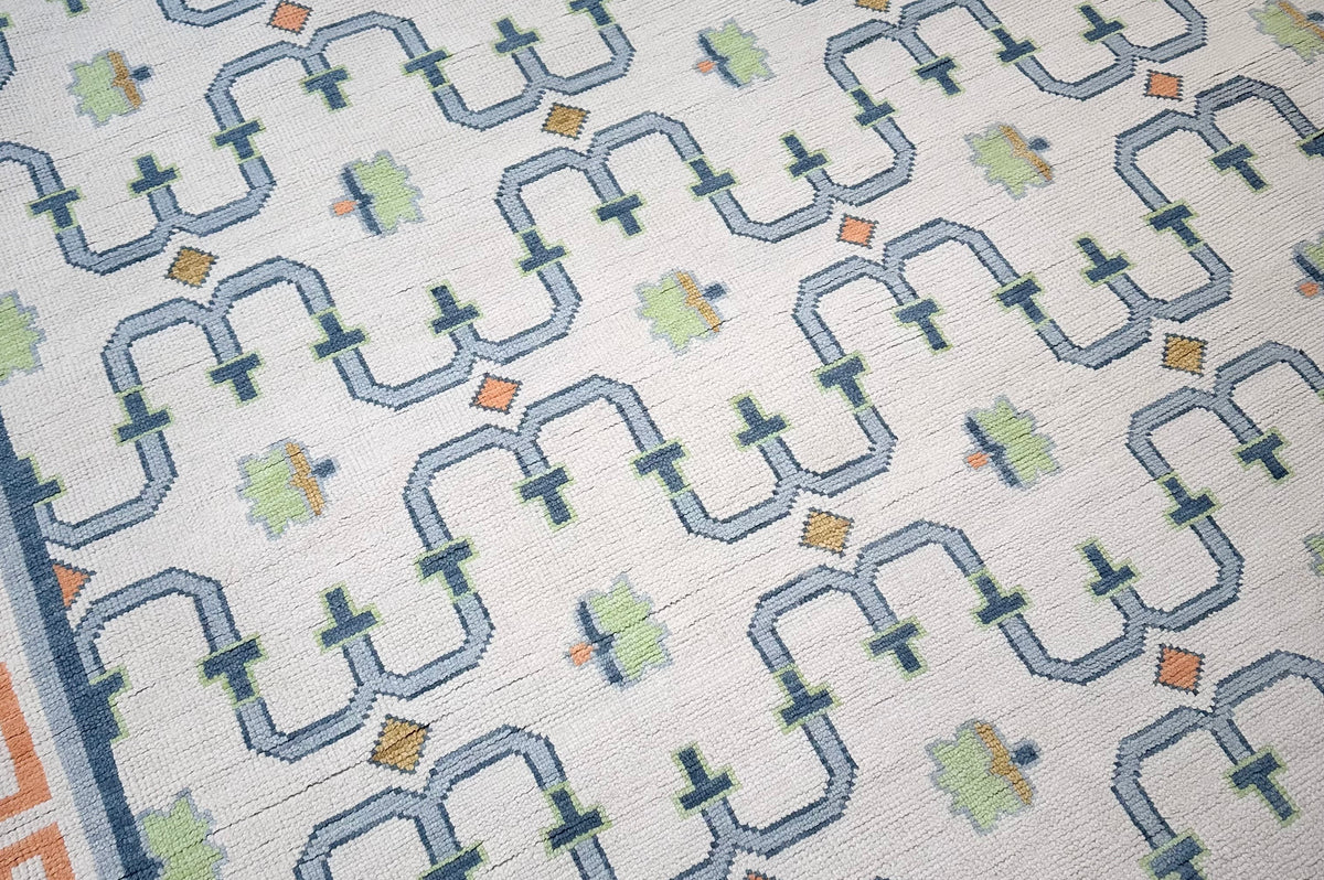 Close-up of oushak wool rug with Greek key design in orange and blue