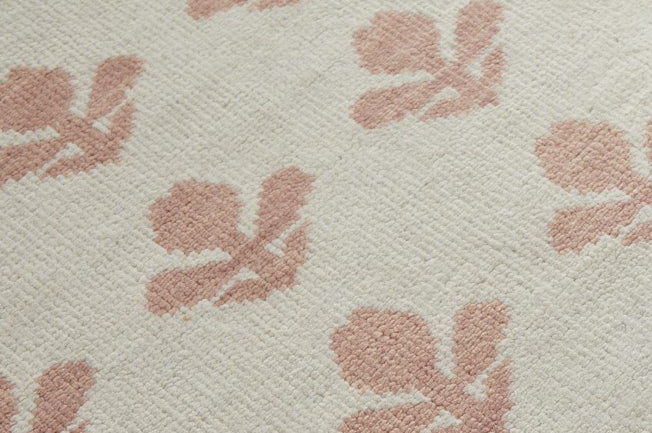 Wool rug with pink floral pattern on a beige background