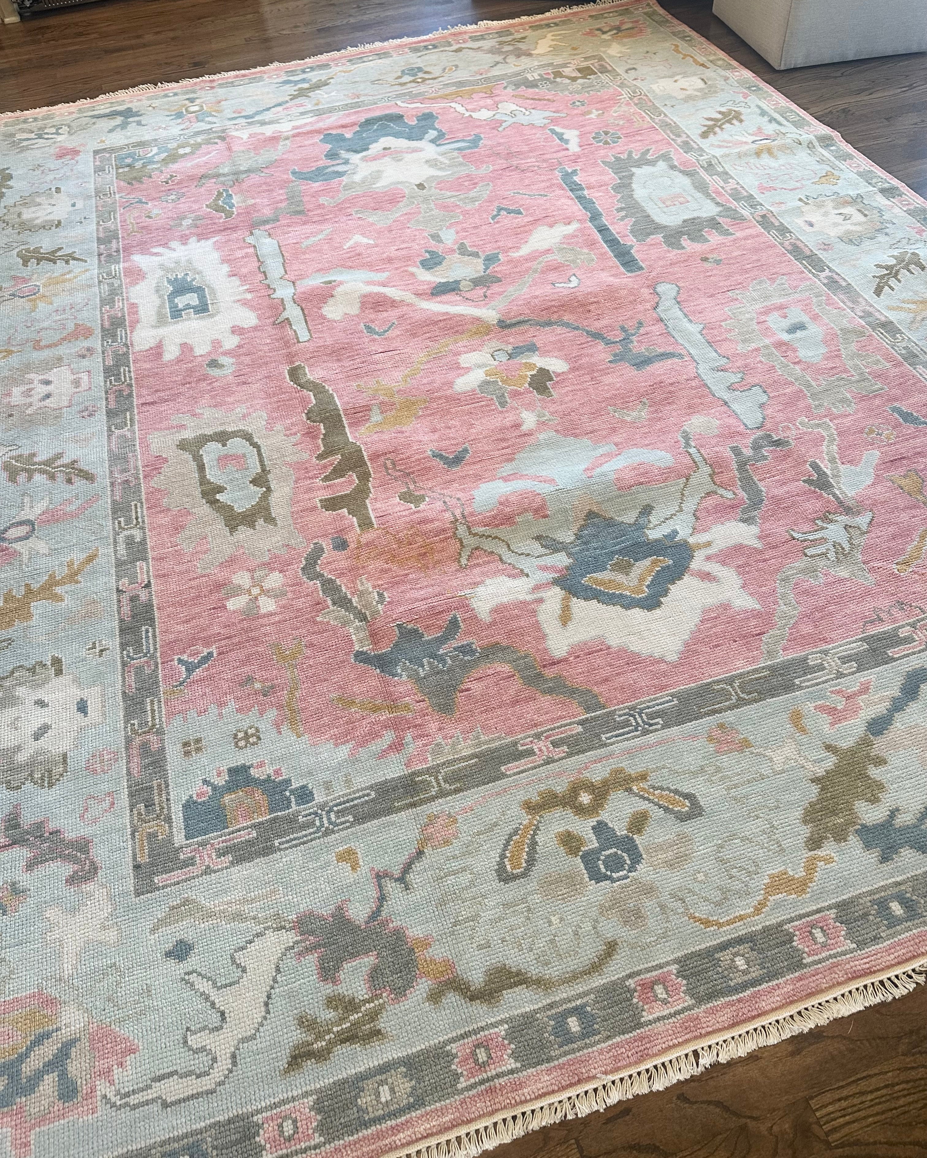 A close-up view of a colorful modern Oushak rug featuring floral patterns in multiple colors including pink, blue, green, and taupe.